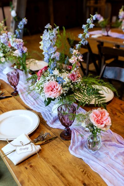 Pastel roses, delphinium and lavender glassware dress the tables before the first guest arrives.