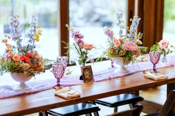 Wildflower centerpieces run the length of the tables beneath the tall barn windows.