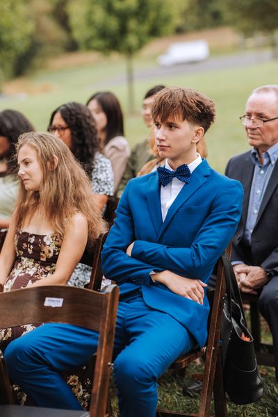 A guest in a bright blue suit watches the ceremony with an easy grin.