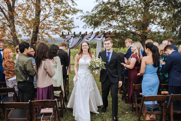 Guests rise and cheer as the newlyweds come back up the aisle.