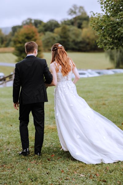 Husband and wife walk off together toward the trees.