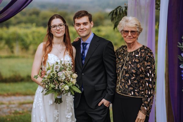 The newlyweds with an elderly woman, all three beaming.