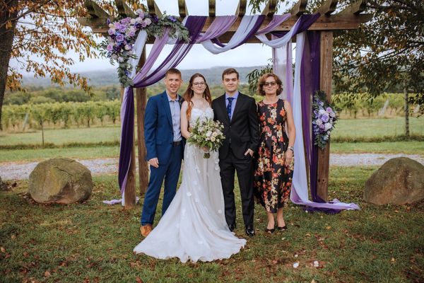 The newlyweds with a man in a blue suit and a woman in a floral dress.