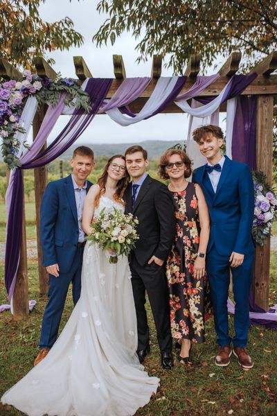 The newlyweds surrounded by family members under the arch.