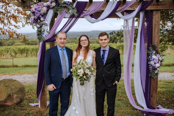 The newlyweds with an older man in a blue suit.