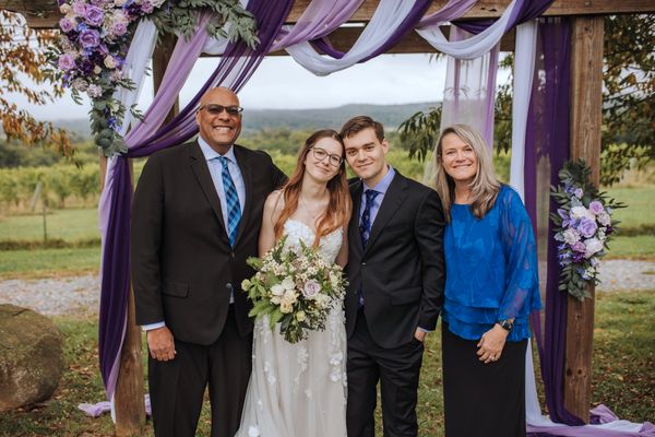 The newlyweds with a man in a dark suit and a woman in blue.