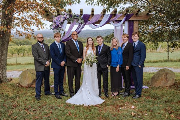 A wider family group gathers around the couple.