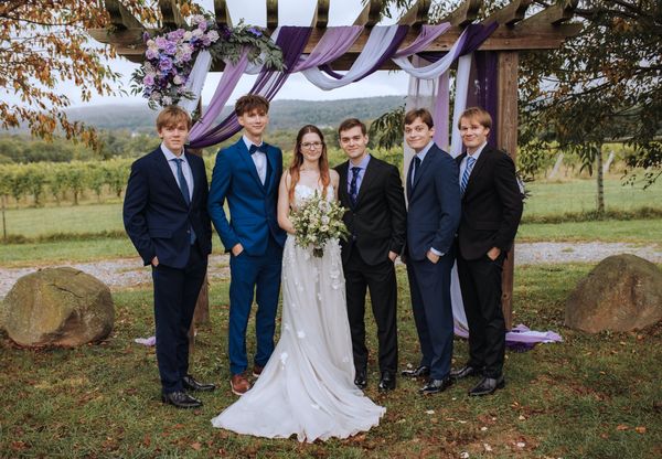 The newlyweds with four young men in suits.