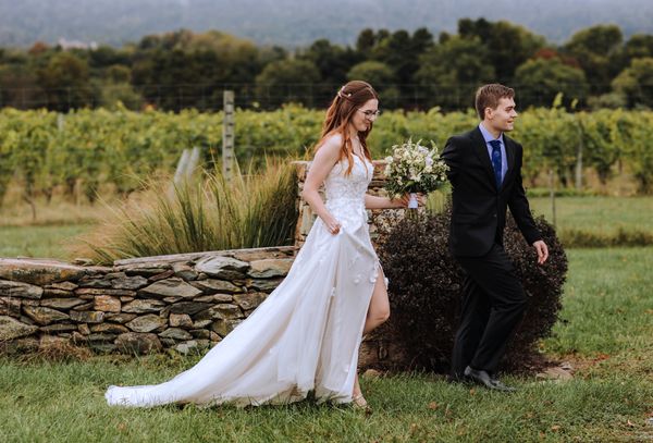 Laughing, the couple strolls along the old stone wall.
