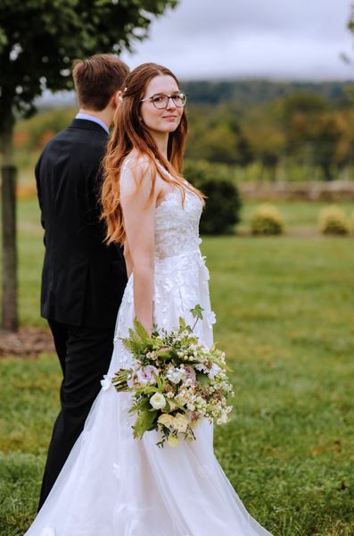 Anastasia looks toward the lens while Brian stands close behind her.