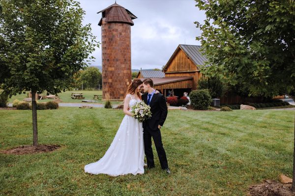 The newlyweds together in front of the old brick silo.