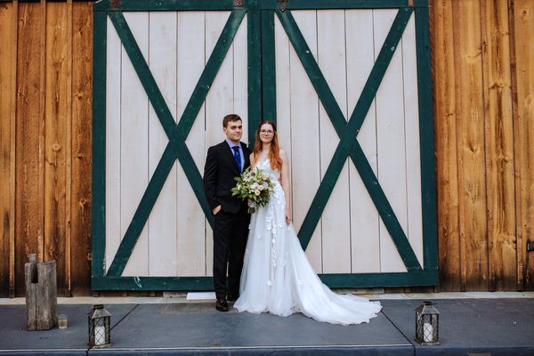The couple poses before the barn's green-trimmed doors.