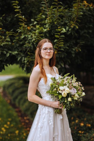 Anastasia alone among the vines, bouquet in hand.