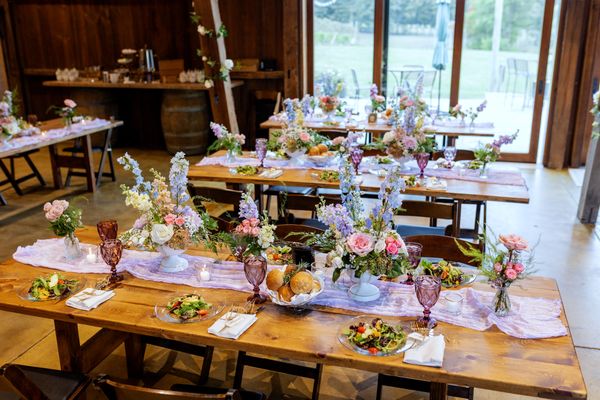 The barn is set for dinner, tables glowing by the windows.