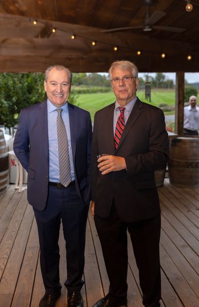 Two men in suits pose on the pavilion.