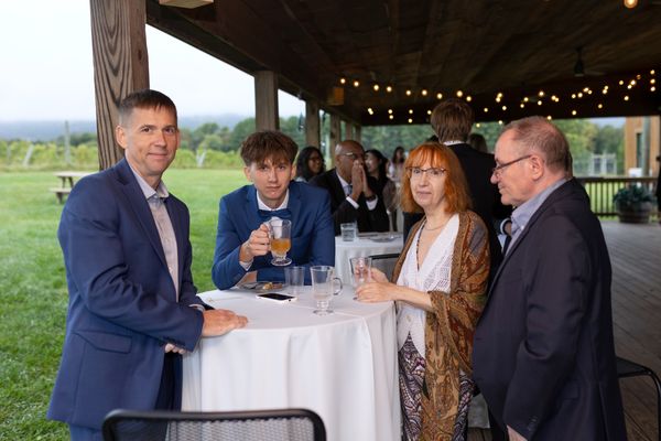 Guests gather around a cocktail table and raise their glasses.