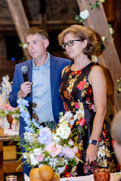 A man and a woman in a floral dress give a toast together.