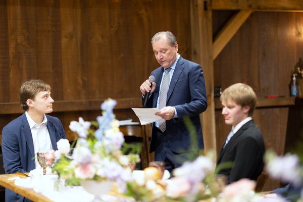 An older man reads his toast, paper in hand.