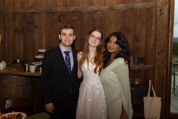 The newlyweds with a guest in a sage-green dress.