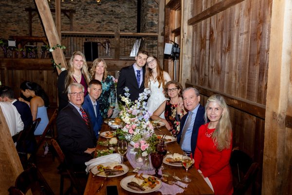A long table of guests gathers for a group photo.