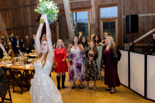 The bride raises her bouquet high before the toss.