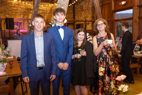 Two young men in blue suits pose with two guests.
